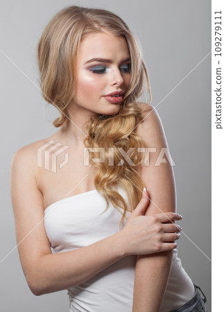 Cheerful young blonde model with long wavy hair, makeup and clean skin on white background. Cheerful young blonde model with long wavy hair, makeup and clean skin on white background. 109279111