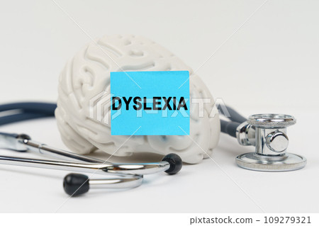 On a white surface next to the stethoscope lies a brain on which a sticker with the inscription - Dyslexia On a white surface next to the stethoscope lies a brain on which a sticker with the inscription - Dyslexia 109279321