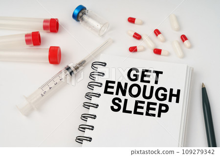 On the table are pills, injections, a syringe and a notepad with the inscription - Get enough sleep 109279342