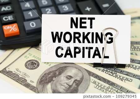 On the dollars there is a calculator and a business card with the inscription - NET WORKING CAPITAL On the dollars there is a calculator and a business card with the inscription - NET WORKING CAPITAL 109279345