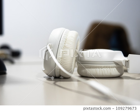 wired headphones close up on a desk with monitors on background.  109279673