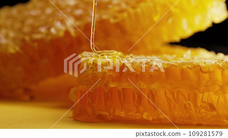 Raw honeycombs with pouring pure golden honey elixir. Amazing tasty flow. Macro. 109281579