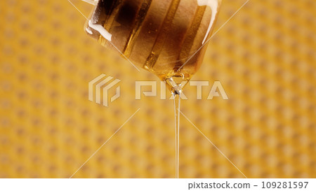 Organic honey flows from wooden dipper stick on honeycombs background. Wax cells Organic honey flows from wooden dipper stick on honeycombs background. Wax cells 109281597