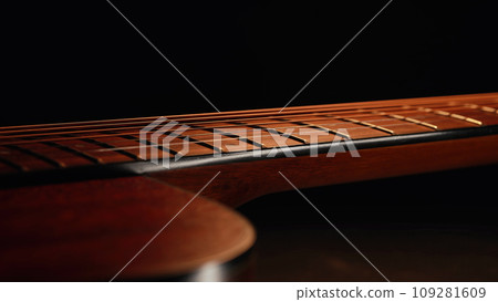 Macro of strings on redwood acoustic guitar fretboard. Classical music, sound Macro of strings on redwood acoustic guitar fretboard. Classical music, sound 109281609