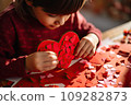 Kid making heart-shaped Valentine's card 109282873