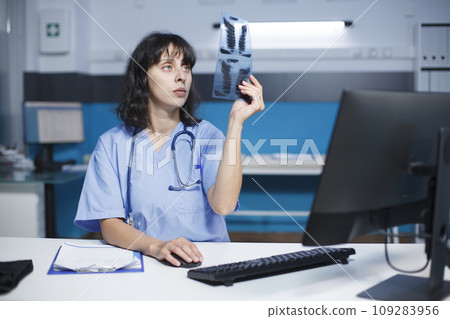 Selective focus of a caucasian nurse practitioner holding and examining a chest X-ray image of a patient. Close-up shot of a female physician grasping and studying a chest scan of an individual. 109283956