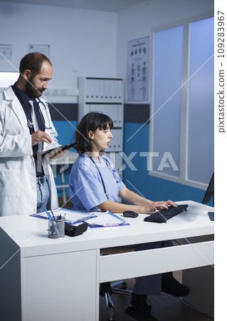 Caucasian doctor and female healthcare worker collaborating in a hospital office. They discuss medical cases, using digital devices for communication and showing images on a tablet. Caucasian doctor and female healthcare worker collaborating in a hospital office. They discuss medical cases, using digital devices for communication and showing images on a tablet. 109283967