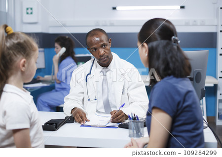 In hospital office, doctor consults with a caucasian woman and her daughter, discussing a medical condition, and providing advice and treatment options. Professional and caring atmosphere. In hospital office, doctor consults with a caucasian woman and her daughter, discussing a medical condition, and providing advice and treatment options. Professional and caring atmosphere. 109284299