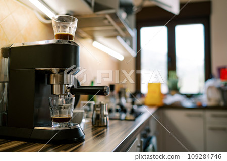 Black coffee dripping from a carob coffee maker into a glass on a stand Black coffee dripping from a carob coffee maker into a glass on a stand 109284746