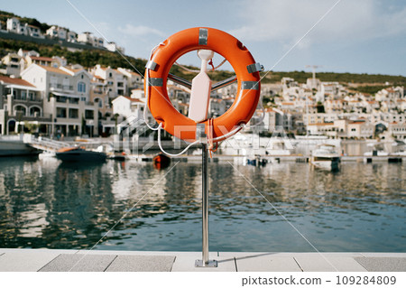 Lifebuoy on a stand with a latch stands on a pier in Lustica Bay. Montenegro 109284809