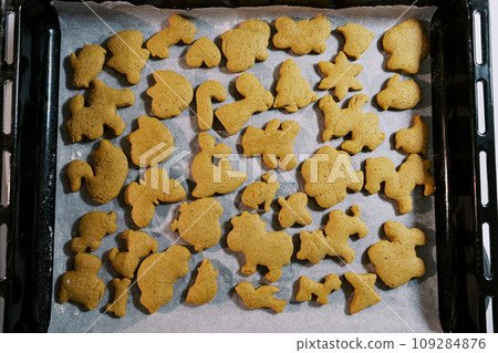 Freshly baked Christmas cookies lie on baking paper on a baking sheet. Top view Freshly baked Christmas cookies lie on baking paper on a baking sheet. Top view 109284876