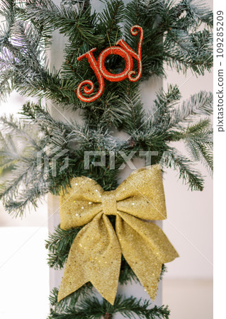 Christmas decoration from coniferous branches and a bow on a pole. Inscription: Joy 109285209