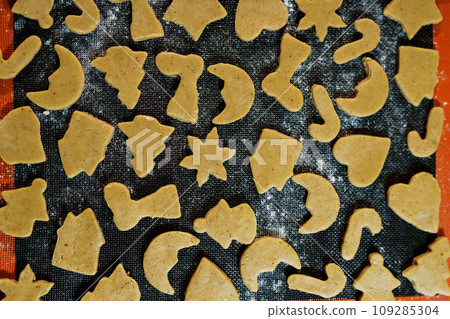 Unbaked gingerbread cookies of various shapes on a baking sheet. Top view Unbaked gingerbread cookies of various shapes on a baking sheet. Top view 109285304