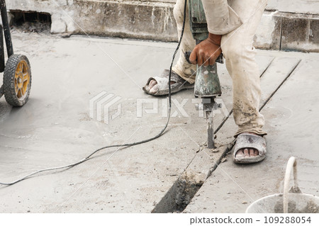 Construction worker using jackhammer drilling concrete surface Construction worker using jackhammer drilling concrete surface 109288054