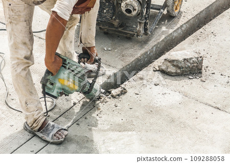Construction worker using jackhammer drilling concrete surface Construction worker using jackhammer drilling concrete surface 109288058