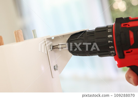 man assembling white table furniture at home using cordless screwdriver man assembling white table furniture at home using cordless screwdriver 109288070