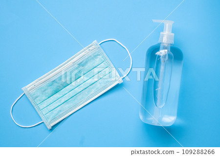 Alcohol hand sanitizer gel bottle with surgical face mask on blue background protection against COVID-19 coronavirus. Healthcare and medical concept Alcohol hand sanitizer gel bottle with surgical face mask on blue background protection against COVID-19 coronavirus. Healthcare and medical concept 109288266