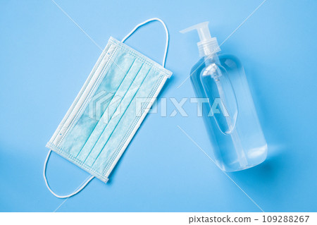 Alcohol hand sanitizer gel bottle with surgical face mask on blue background protection against COVID-19 coronavirus. Healthcare and medical concept 109288267