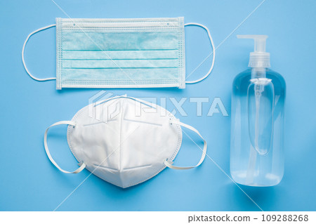 Alcohol hand sanitizer gel bottle with KN95 surgical face mask on blue background protection against COVID-19 coronavirus. Healthcare and medical concept 109288268