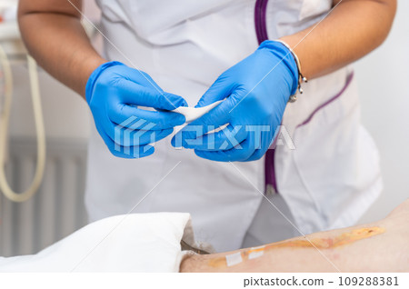 hand of Doctor is using clean cotton dressing infection wound at a man abdomen. Bandage for wound hand of Doctor is using clean cotton dressing infection wound at a man abdomen. Bandage for wound 109288381