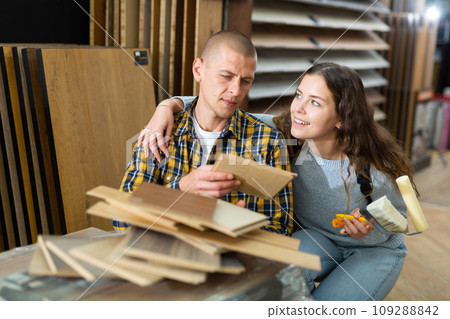 Couple with sample of laminated flooring in building store Couple with sample of laminated flooring in building store 109288842