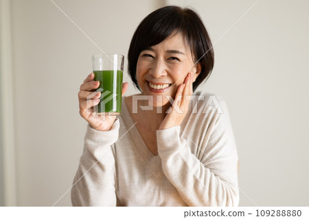 A woman drinking green juice/vegetable juice A woman drinking green juice/vegetable juice 109288880