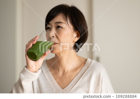 A woman drinking green juice/vegetable juice 109288884