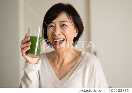 A woman drinking green juice/vegetable juice 109288885