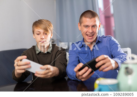 Boy with father resting and playing on phone Boy with father resting and playing on phone 109289005