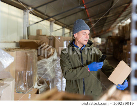 Storekeeper using his phone to take photograph of pasteboard box 109289019