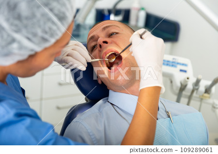 Dentist inspects male patient teeth Dentist inspects male patient teeth 109289061