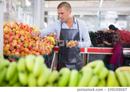Merchandiser setting out plums in greengrocery 109289087