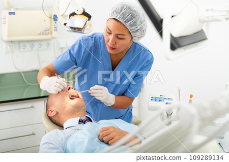 Focused woman dentist treats a man patient 109289134