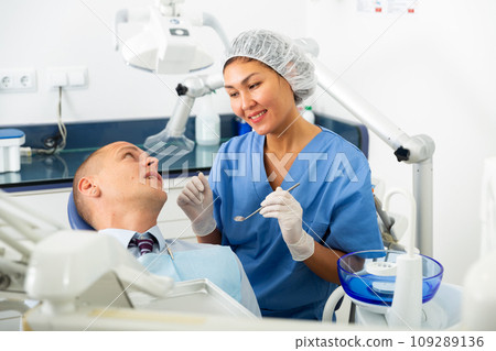 Dentist inspects male patient teeth 109289136