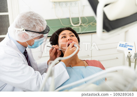Dentist drilling tooth to asian female patient 109289163