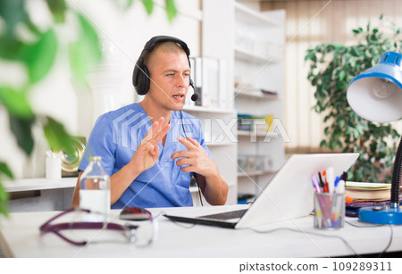 Male doctor listening to patient during telemedicine session in clinic Male doctor listening to patient during telemedicine session in clinic 109289311