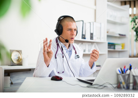 Male doctor listening to patient during telemedicine session in clinic 109289332