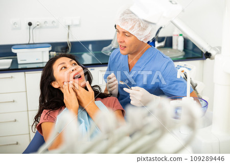 Female patient shows sick tooth to a dentist in dental clinic 109289446