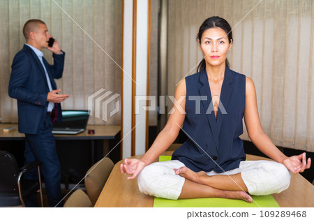 Businesswoman sitting at the table in lotus position 109289468