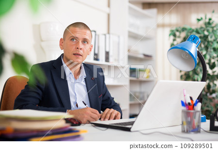 Focused young man working on laptop at office desk Focused young man working on laptop at office desk 109289501