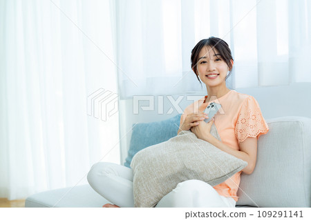 A young woman operating a smartphone in a room 109291141