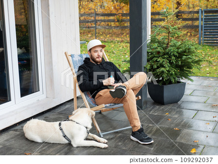 Young man sitting with dog on terrace. 109292037