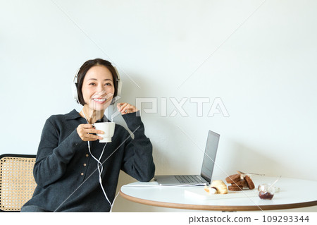 A woman wearing headphones and working remotely 109293344