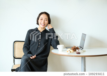 一位女士一邊喝茶一邊用電腦工作 109293811