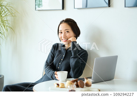 A woman working on a computer while drinking tea 109294227