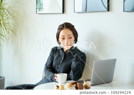 一位女士一邊喝茶一邊用電腦工作 109294229