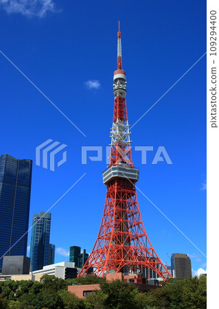 Tokyo Tower with the new Toranomon Hills building in the background on a sunny day against a blue sky as seen from Shiba Park in Tokyo, Japan Tokyo Tower with the new Toranomon Hills building in the background on a sunny day against a blue sky as seen from Shiba Park in Tokyo, Japan 109294400