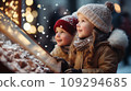 Two small children a boy and a girl on a snowy winter street are looking at a shop window 109294685
