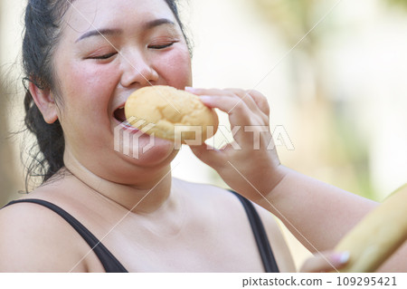 Cheerful two woman overweight in sportswear have fun and enjoy eating bread while exercising Cheerful two woman overweight in sportswear have fun and enjoy eating bread while exercising 109295421