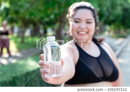 women overweight in sportswear drinking water in bottle after exercise in garden, women overweight in sportswear drinking water in bottle after exercise in garden, 109295522